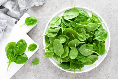 Taze ıspanak üzerinde beyaz tabak bırakır. Sağlıklı vegan gıda. Üstten görünüm