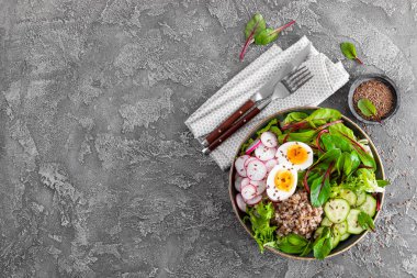 Buda kase yemek buğday lapası, haşlanmış yumurta, taze sebze salatası, turp, salatalık, marul ve pazı yaprakları. Sağlıklı öğle yemeği menüsü. Üstten Görünüm