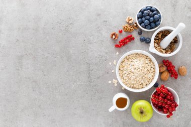 Taze çilek, yaban mersini, frenk üzümü, ceviz ve ballı yulaf ezmesi yemek. Sağlıklı vejetaryen kahvaltı gıda kavramı, üstten görünüm, düz yatıyordu