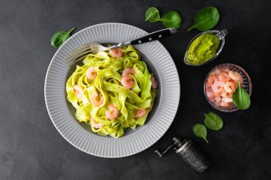 Taze ıspanak pesto ve siyah arka plan üzerine karides ile haşlanmış fettuccine makarna. İtalyan mutfağı. Sağlıklı yemek yemek için. Üstten Görünüm