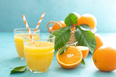 Turuncu taze cam ve taze meyve mavi canlı arka plan üzerinde sıkılmış suyu