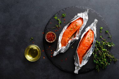 Siyah arka plan üzerinde folyo çiğ somon balık fileto