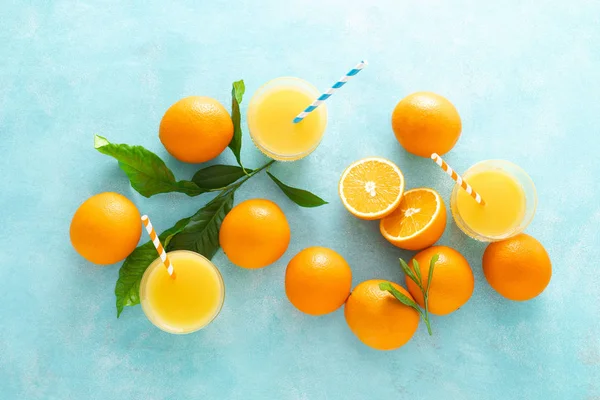 Orange freshly squeezed juice in glass and fresh fruits on a blue vivid background, top view