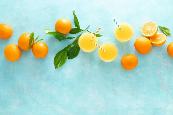 Orange freshly squeezed juice in glass and fresh fruits on a blue vivid background, top view