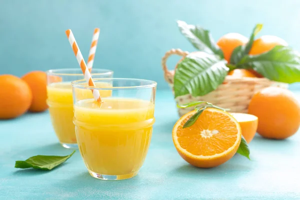 Orange freshly squeezed juice in glass and fresh fruits on a blue vivid background