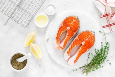 Beyaz tahta üzerinde yemek pişirmek için malzemelerle taze somon biftek, yukarıdan görünümü