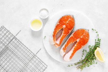 Beyaz tahta üzerinde yemek pişirmek için malzemelerle taze somon biftek, yukarıdan görünümü