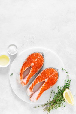 Beyaz tahta üzerinde yemek pişirmek için malzemelerle taze somon biftek, yukarıdan görünümü