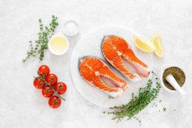 Beyaz tahta üzerinde yemek pişirmek için malzemelerle taze somon biftek, yukarıdan görünümü