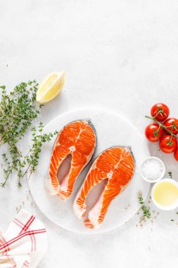 Beyaz tahta üzerinde yemek pişirmek için malzemelerle taze somon biftek, yukarıdan görünümü