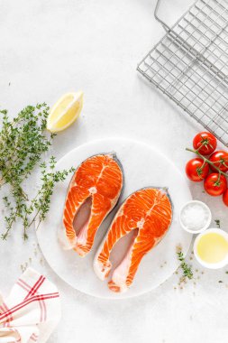 Beyaz tahta üzerinde yemek pişirmek için malzemelerle taze somon biftek, yukarıdan görünümü