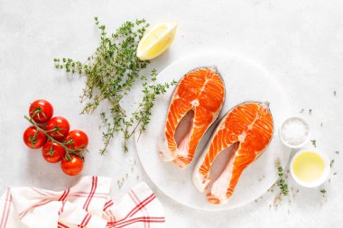 Beyaz tahta üzerinde yemek pişirmek için malzemelerle taze somon biftek, yukarıdan görünümü