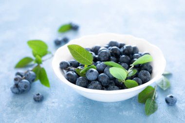 Mavi arka planda beyaz kase yaprakları ile yaban mersini, üst görünüm