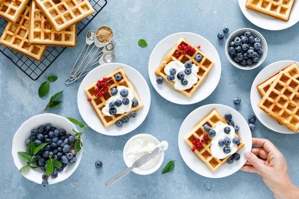 Traditional belgian waffles with cream cheese and fresh blueberry on blue background, top view