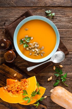 Balkabağı çorbası. Ahşap masada kase kabak çekirdeği ile Vejetaryen çorbası, üst görünümü