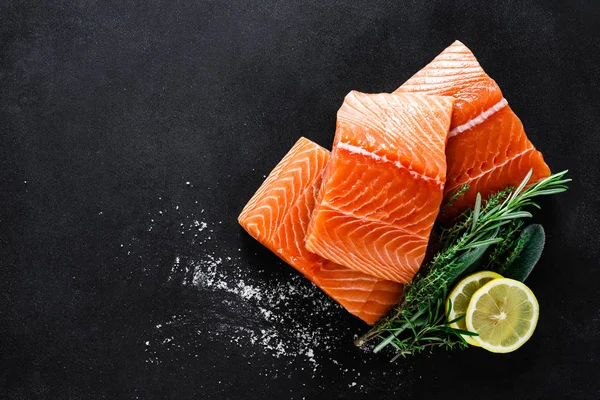 新鲜的生鲑鱼鱼片与烹饪成分 草药和柠檬的黑色背景 顶视图 — 图库照片