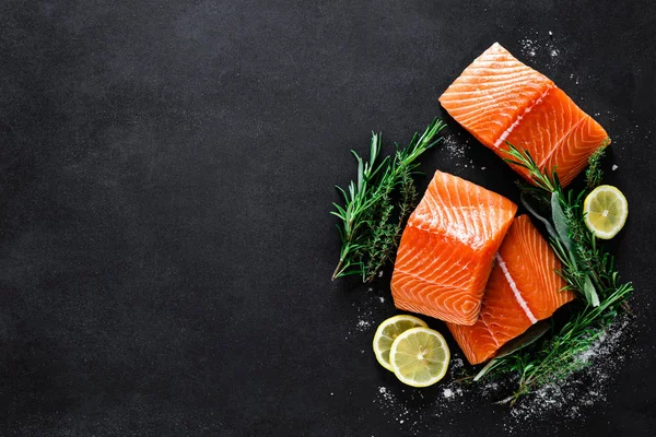 新鲜的生鲑鱼鱼片与烹饪成分 草药和柠檬的黑色背景 顶视图 — 图库照片