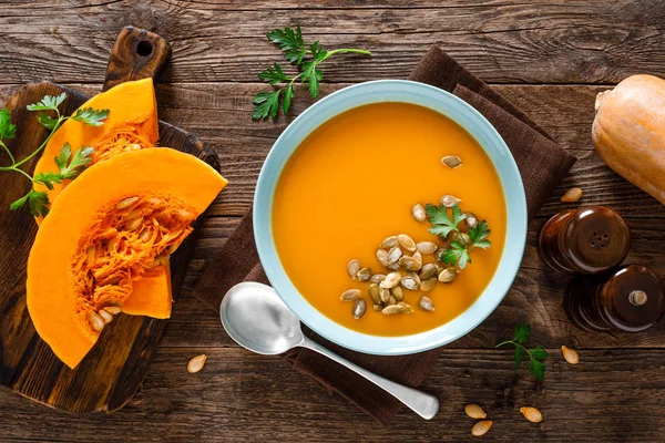 Pumpkin soup. Vegetarian soup with pumpkin seeds in bowl on wooden table, top view