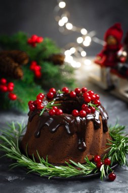 Taze çilek ve biberiye ile dekore sır ile Noel çikolata bundt kek. Xmas veya Yeni Yıl koyu arka plan süslemeleri ile Kış pişirme