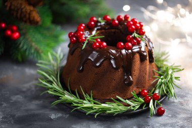Taze çilek ve biberiye ile dekore sır ile Noel çikolata bundt kek. Xmas veya Yeni Yıl koyu arka plan süslemeleri ile Kış pişirme