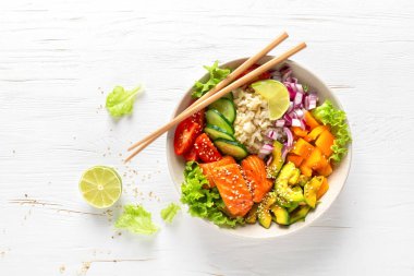 Izgara somon balıklı Buda kasesi, taze salatalık, domates, soğan, tatlı biber, avokado, marul salatası ve pirinç, sağlıklı dengeli yemek.