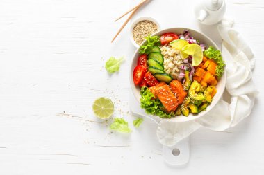 Izgara somon balıklı Buda kasesi, taze salatalık, domates, soğan, tatlı biber, avokado, marul salatası ve pirinç, sağlıklı dengeli yemek.