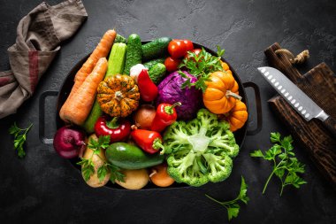 Mutfak arka planında siyah mutfak masasında taze çiğ sebzeler, sağlıklı vejetaryen yemek konsepti, düz kompozisyon, üst görünüm