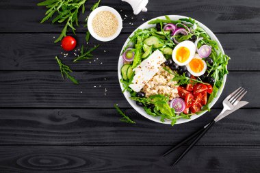 Yunan usulü sağlıklı kahvaltı kasesi yulaf lapası ve taze sebze salatası, marul, roka, zeytin, domates, salatalık, peynir ve haşlanmış yumurta.