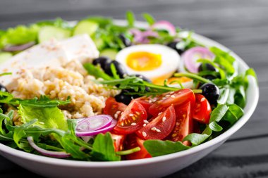 Yunan usulü sağlıklı kahvaltı kasesi yulaf lapası ve taze sebze salatası, marul, roka, zeytin, domates, salatalık, peynir ve haşlanmış yumurta.