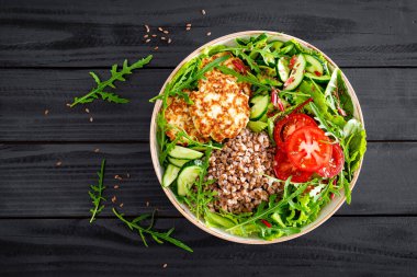 Karabuğday lapası, kızarmış tavuk pirzolası ve taze roka salatası, marul, meyve yaprağı, domates, salatalık ve keten tohumu.