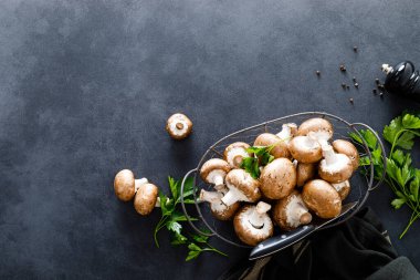 Siyah arka planda çiğ mantar şampiyonları taze şampiyon pişiriyor.