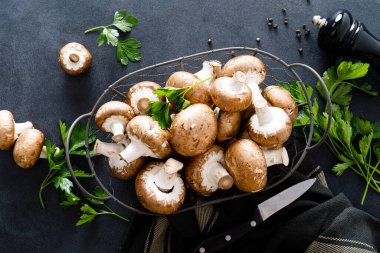 Siyah arka planda çiğ mantar şampiyonları taze şampiyon pişiriyor.