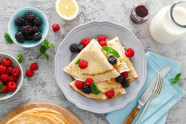 Thin crepes with fresh berries and lemon zest. Pancakes with raspberry and blackberry