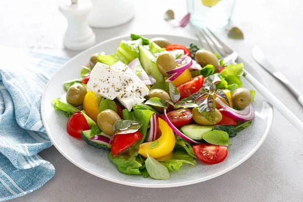 Greek salad. Fresh vegetable salad of cucumbers, tomatoes, olives, onion, bell pepper, feta cheese, lettuce and herbs and dressed with salt, pepper and olive oil. Popular greek Horiatiki salad