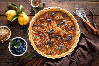 Thanksgiving pear tart, pie or cake with fresh pears and blueberry, cinnamon and walnuts clipart