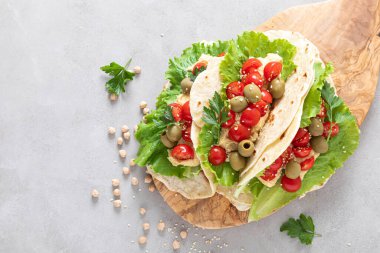 Nohut humuslu tortilla, taze domates ve zeytin, vejetaryen yemeği.