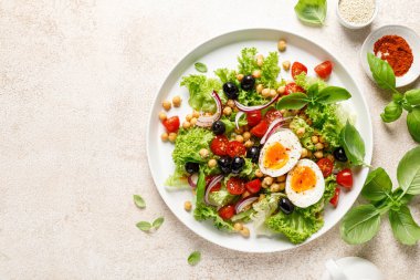 Yumuşak haşlanmış yumurta taze sebze salatası, domates, nohut, zeytin, soğan ve yeşil marul. Sağlıklı yemek, kahvaltı. Üst görünüm