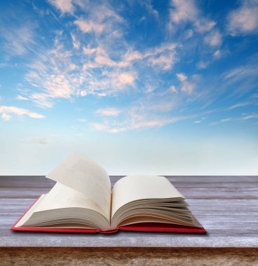 Gökyüzü önünde masada açık kitap
