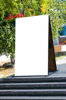 Yazın bir şehir caddesinde boş beyaz reklam düzeni. Alanın bir kopyasıyla ahşap billboard reklamı. Güneş tarafından aydınlatılan, taklit edilen, aydınlatılan.