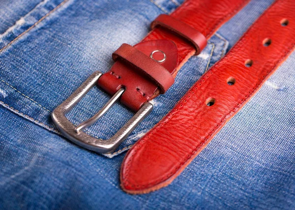 A belt lying on denim. Fashionable red belt close-up. — Stock Photo, Image