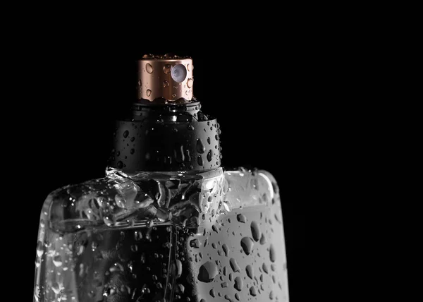 Бутылка духов с капельками свежести на черном фоне . — стоковое фото