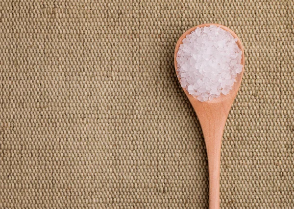 Zout in een houten lepel op een textiel achtergrond — Stockfoto