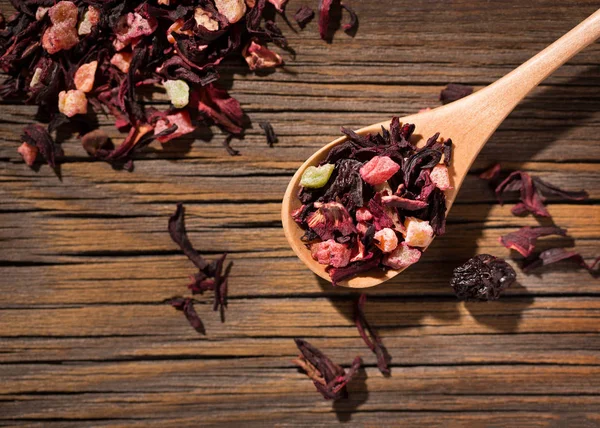 Hibiscus tea. Dry mix of red herbal and fruit tea over wooden su