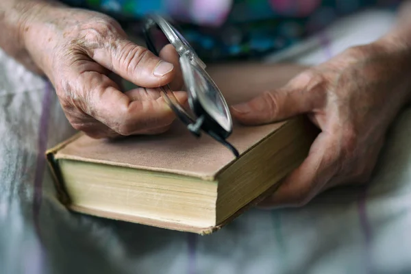 Emerytka czytania książki. Ręce osoby starszej bliska. — Zdjęcie stockowe