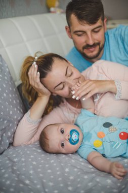 Evde bebekle mutlu genç ebeveynlerin portresi.