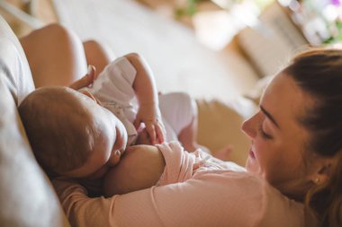 Genç anne bebeğini evde emziriyor.