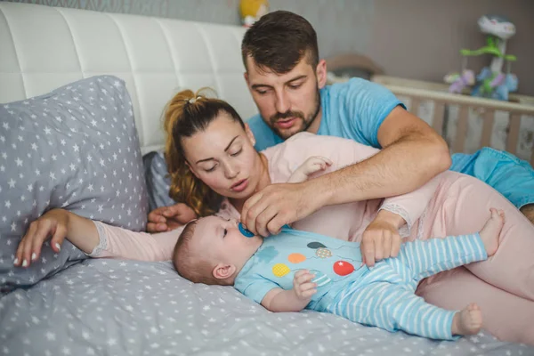 Evde bebekle mutlu genç ebeveynlerin portresi.