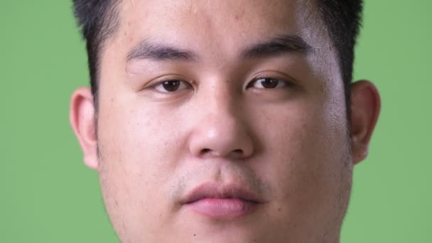 Young handsome overweight Asian man against green background — Stock Video