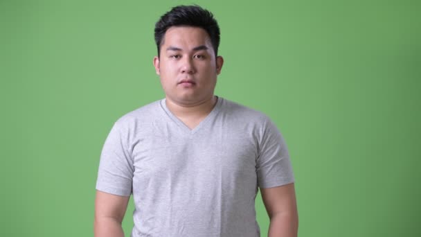 Jeune bel homme asiatique en surpoids sur fond vert — Video