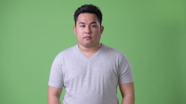 Joven guapo sobrepeso asiático hombre contra verde fondo — Vídeos de Stock